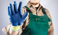 Worker In Green Overall Outfit Showing Blue Protective Rubber Glove.