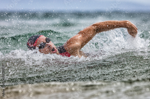 Fotografía Triathlon swim tired swimmer swimming in ocean in wave and rain storm