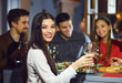 © Studio Romantic - Woman with a glass against the background of friends in a restaurant.
