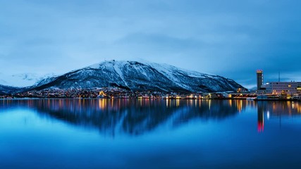 Sticker - Tromso, Norway. Time-lapse at night of famous north town Tromso, Norway. View of the fjord with illuminated houses and mountain, cloudy blue sky at sunrise in the morning, zoom in