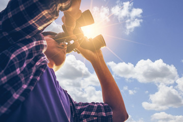 close-up of asian man hand holding / looking / watching using binoculars with copyspace, technology 