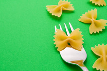Silver Fork With Farfalle On A Green Background With Pasta Around With Copyspace