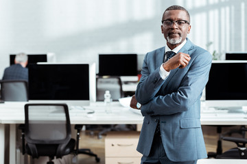 selective focus of african american businessman in glasses and formal wear standing in office