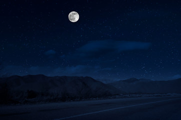 Wall Mural - mountain road through the forest on a full moon night. scenic night landscape of country road at nig