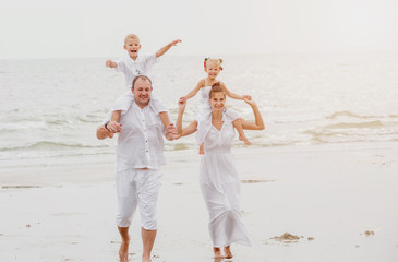 Wall Mural - Happy young family on the sunset at the beach.