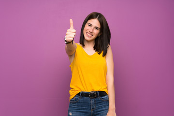 Wall Mural - Young woman over isolated purple wall with thumbs up because something good has happened