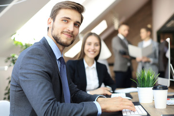 Businessman with colleagues in the background in office.