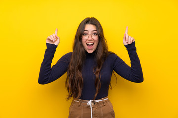 Wall Mural - Teenager girl over isolated yellow wall pointing up a great idea