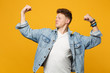 © ViDi Studio - Portrait of strong young man in denim casual clothes looking aside, showing biceps, muscles isolated on yellow orange wall background. People sincere emotions lifestyle concept. Mock up copy space.
