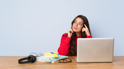 Teenager student girl studying in a table having doubts and thinking