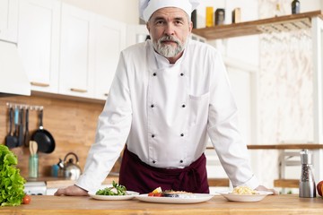 Poster - Attractive Caucasian chef standing in a restaurant kitchen