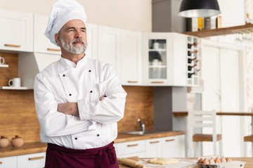 Wall Mural - Attractive Caucasian chef standing with arms crossed in a restaurant kitchen