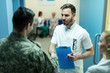 Male doctor handshaking with army soldier while greeting at clinic.