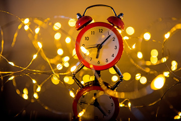 Wall Mural - Alarm Clock And Christmas Lights Against Blurred Background. Winter Night