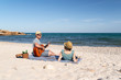 © Esther Pueyo - Couple in love having a picnic and playing the guitar at a mediterranean beach at sunset. Romantic weekend