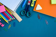 © Anna - School supplies on blue background. Top view. Copy space.