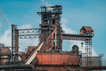 Iron tower constructions and pipes with smog of metallurgical plant as industrial background. Pollution from heavy industry