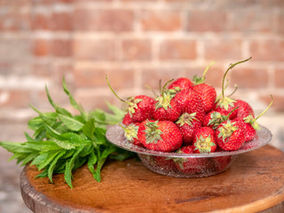 Wall Mural - plate with strawberries and mint on a brick wall background
