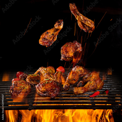 Fotografía Tasty chicken legs and wings on the grill with fire flames