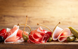 Fototapeta  - Assorti of sliced jamon, salami, ham with olives ,capers, pickles and stuffed red peppers
