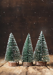 Poster - Merry Christmas with xmas tree and snow falling on grunge wood table and dark brown wooden wall.winter holiday greeting card