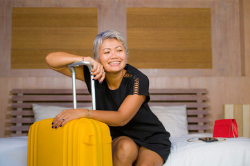 portrait of happy and attractive 40s to 50s mature Asian tourist woman with grey hair arriving in hotel room in business or vacation trip smiling cheerful