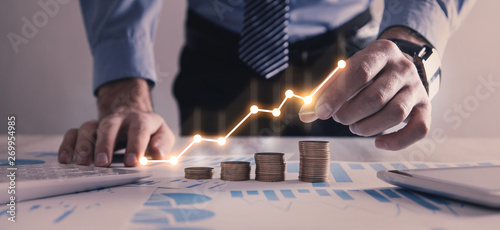 Cuadros en Lienzo Man stacking coins with a graph of profit.