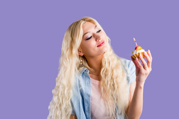 Wall Mural - Happy lovely curly young woman holding birthday cupcake with candle