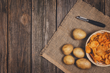 Heap of potato chips in vintage bowl on old wooden table background close-up with copy space for your text