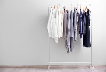 rack with stylish clothes near light wall