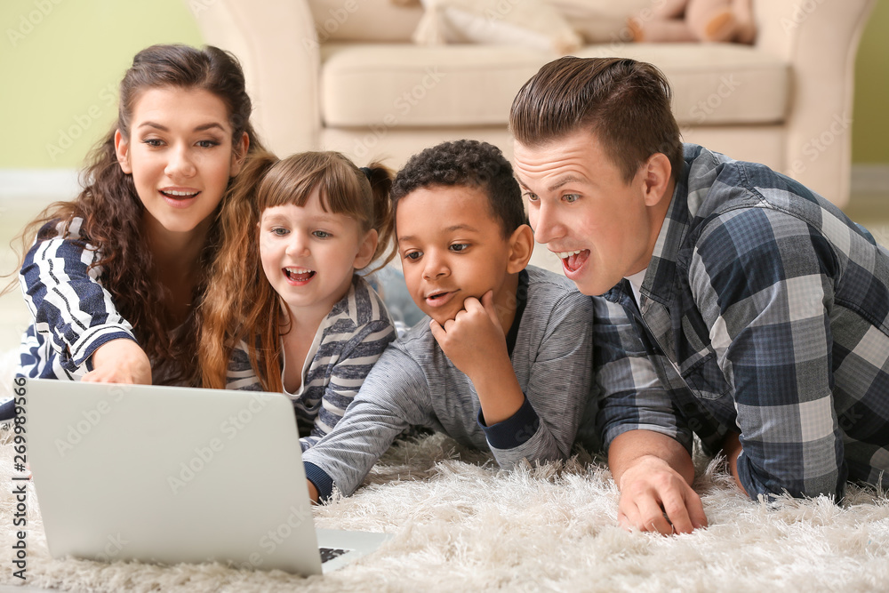 Happy couple with little adopted children using laptop at home