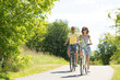 © Syda Productions - people, leisure and lifestyle concept - happy young couple riding bicycles along road in summer