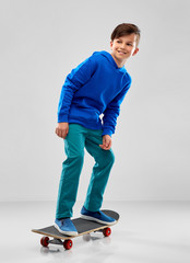 Wall Mural - childhood, leisure and people concept - smiling boy in blue hoodie with skateboard over grey background