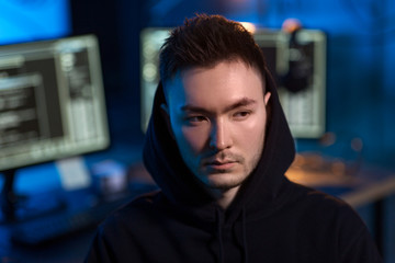 Poster - cybercrime, hacking and technology concept - young asian hacker wearing hoodie in dark room with computers at night