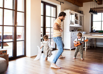 a father and toddler children playing indoors at home.