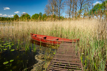 Wooden Red Rowboat Moored To A Rustic Jetty