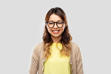 Poster - people, education and school concept - happy asian woman in glasses or student over grey background