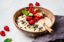 Chia Pudding With Berries, Banana, Peanut Butter And Cocoa Nibs In Coconut Shell Bowl.