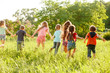 © Andrey - a group of children playing and running in the park on a green gozon.