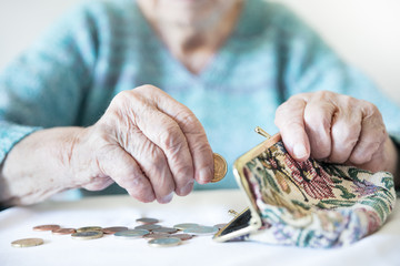 Detailed closeup photo of elderly 96 years old womans hands counting remaining coins from pension in her wallet after paying bills. Unsustainability of social transfers and pension system.