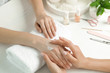 © New Africa - Cosmetologist applying cream on woman's hand at table in spa salon, closeup