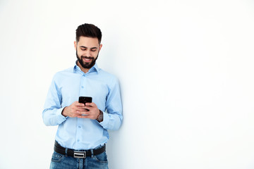 Sticker - Handsome young man using phone near white wall, space for text. Working time