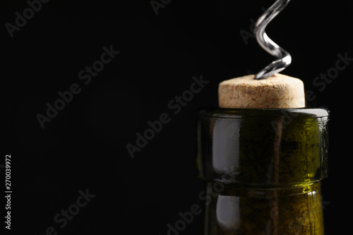 Fotomural Opening wine bottle with corkscrew on black background, closeup