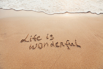 Life is wonderful, positive thinking concept. Inspirational quote written on sand.