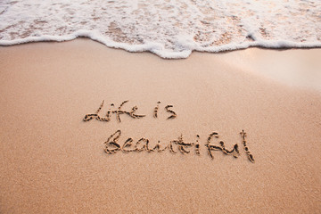 Life is beautiful, positive thinking concept. Inspirational quote written on sand.