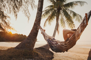 tourist relaxing in hammock on tropical beach with coconut palm trees, relaxation and leisure touris