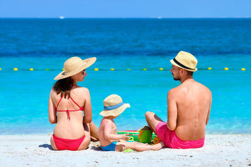 Family on beach. Two year old toddler boy playing with beach toys with mother and father on beach.