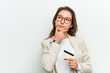 © Asier - Young european business woman holding a credit card looking sideways with doubtful and skeptical expression.