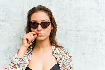 Wall Mural - Young european woman wearing bikini with fingers on lips keeping a secret.