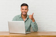 © Asier - Young filipino man sitting working with his laptop smiling and raising thumb up